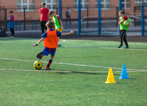 niños jugadores de fútbol practican driblar, patadas en el entrenamiento de fútbol en el campo en el verano
 - Foto, Imagen
