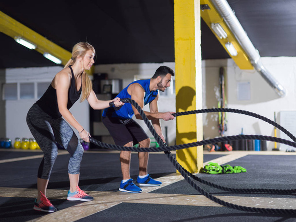sports couple doing battle ropes crossfitness exercise - 写真・画像