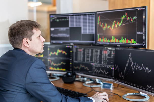 Aktienhändler blickt im trendigen Büro auf Computerbildschirme. - Foto, Bild