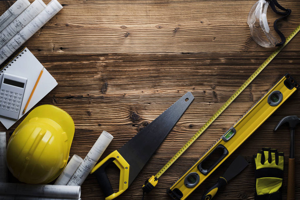 Bau- und Sanierungskonzept. Werkzeuge des Bauunternehmers auf Holztisch. Ansicht von oben.  - Foto, Bild