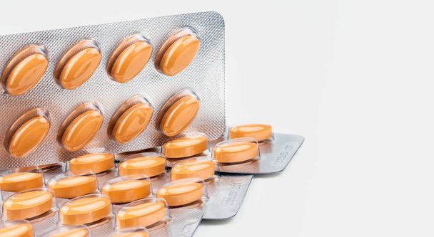 Orange oval tablet pills isolated on white background. Medicine for treating venous circulation disorders (swollen legs, pain, restless legs) and hemorrhoids and acute hemorrhoidal attack. - Фото, изображение