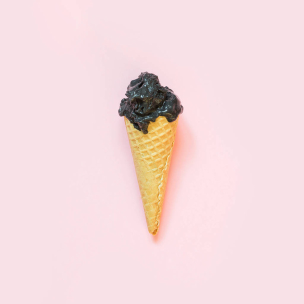 Creative still life of black ice cream in waffle cone on pastel pink background. Spring concept. - Foto, Imagem
