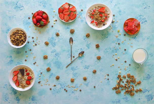 Aardbei, muesli, melk en Turks fruit op een turquoise tafel. Tijd voor het ontbijt. Tijd van lepels weergeven. - Foto, afbeelding