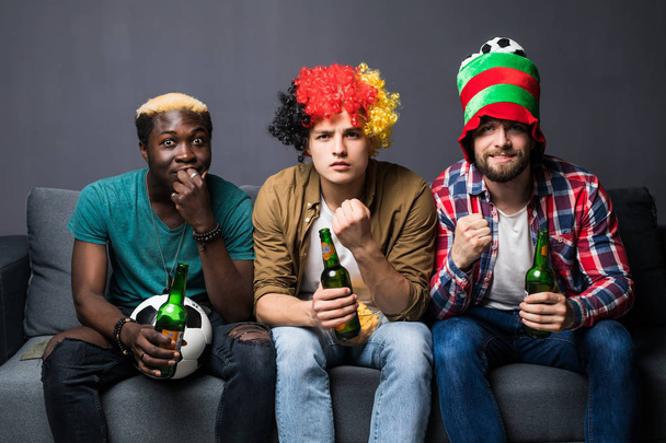 Група молодих чоловіків дивиться футбол вдома і п'є пиво дивиться телевізор
 - Фото, зображення