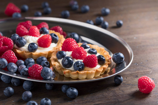  Dessert tarts with raspberries and blueberries on a wooden tabl - Photo, Image