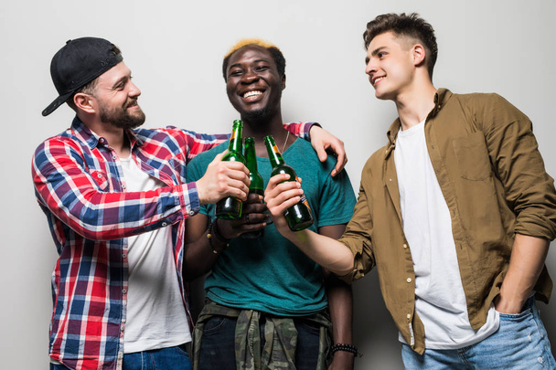 Tři mladíci radostné, které drží pivo a slaví izolované nad šedým pozadím - Fotografie, Obrázek