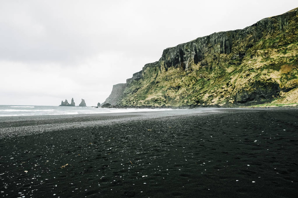 Reynisfjara black sand beach in Vik town in Iceland, surrounded with basalt mountains - Foto, Imagem