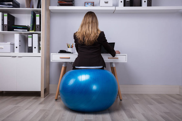 Rear View Of A Businesswoman Sitting On Fitness Ball Working In Office - Zdjęcie, obraz