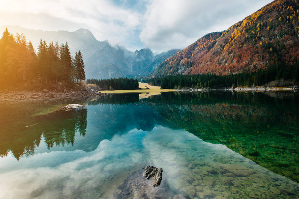 Piękna scena w Lago di Fusine z krystalicznie czystą wodą i górami Mangart w tle. Jesienna sceneria nad jeziorem Fusine w północnych Włoszech - Alpy - Europa - Zdjęcie, obraz