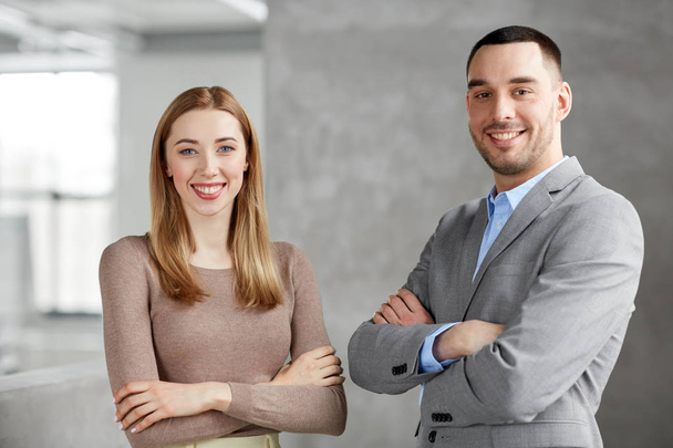 smiling businesswoman and businessman at office - Foto, Imagen