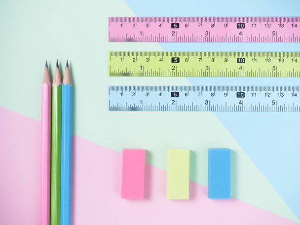 зелений, синій, рожевий гумкою, гумкою та олівцями на зеленому та світло-блакитному та рожевому фоні
. - Фото, зображення