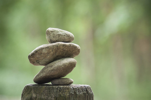 primer plano del equilibrio de piedras en la valla de madera en el respaldo borroso verde
 - Foto, Imagen