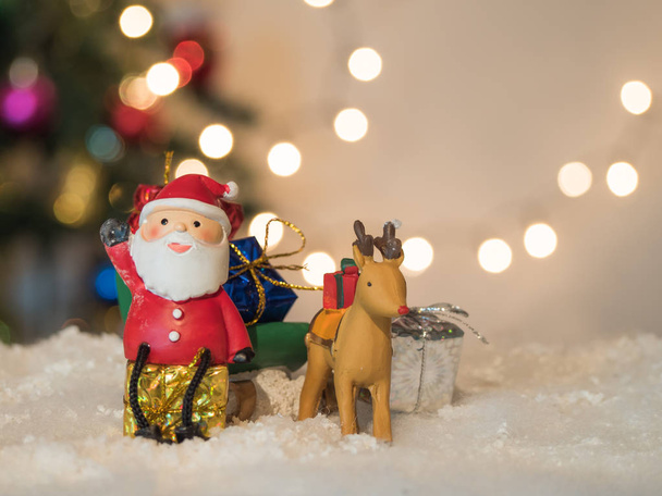 reindeer lug green sleigh  santa claus sit on box gesticulate your hand and bokeh background - Zdjęcie, obraz