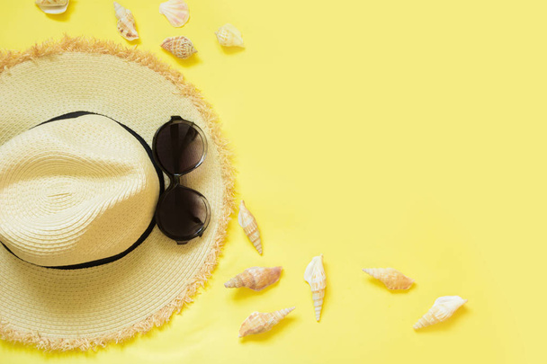 Straw beach foman's hat and black sun glasses with seashells on yellow background. Top view. Flat lay. - Fotoğraf, Görsel