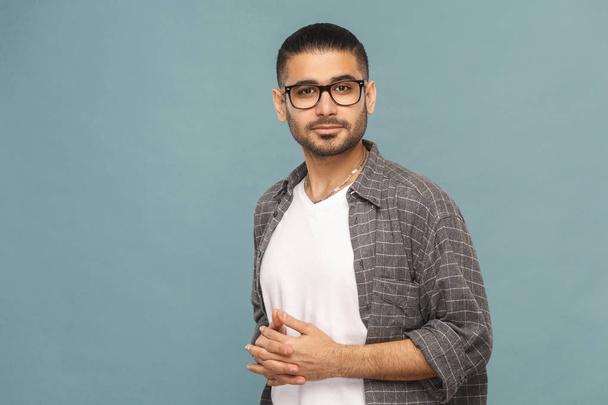 bearded handsome man with black glasses in casual style looking at camera and smiling on blue background - Foto, immagini