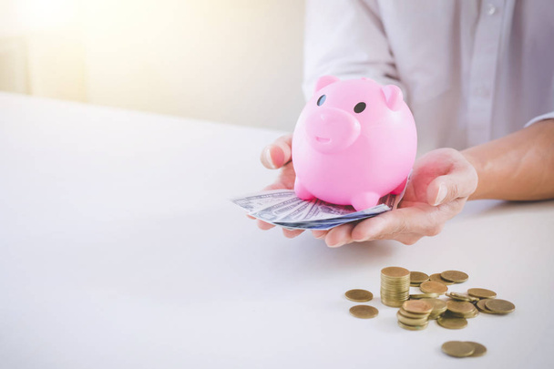 Businessman saving coins into piggy bank and using calculator to - Фото, зображення