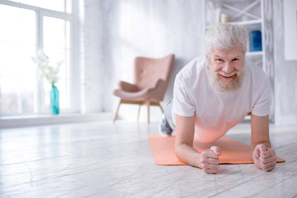 Cheerful elderly man doing plank exercise - Zdjęcie, obraz