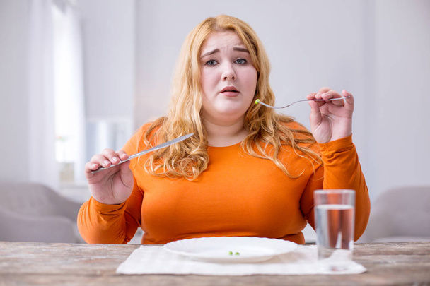 Unhappy overweight woman eating peas - Fotó, kép