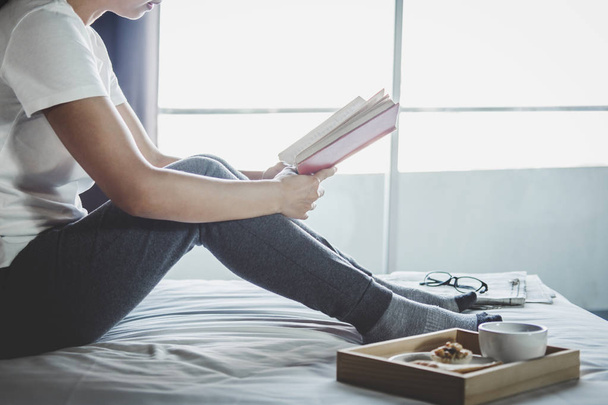 Young woman happiness on bedroom in enjoying reading books and n - Photo, Image