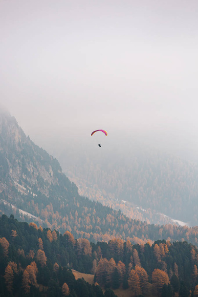 Paralotnia latająca nad górami w dolomitach we Włoszech. Słoneczny jesienny dzień. - Zdjęcie, obraz