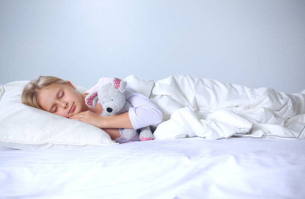 Child little girl sleeps in the bed with a toy teddy bear. - Φωτογραφία, εικόνα