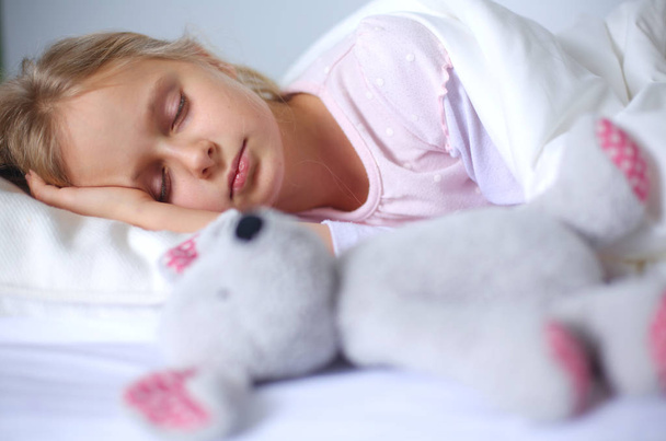 Child little girl sleeps in the bed with a toy teddy bear. - Foto, Imagen