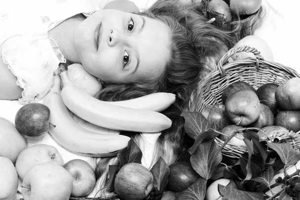 cute baby girl laying with colorful fruits in basket - 写真・画像