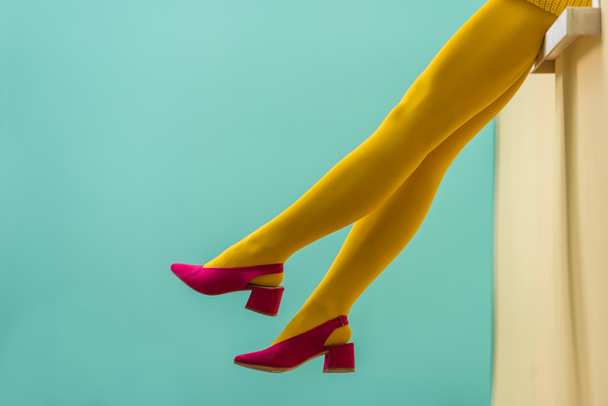 partial view of woman in yellow tights and pink shoes on blue backdrop - Photo, Image