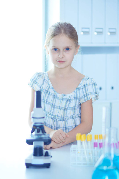 Schoolgirl looking through microscope in science class. - Foto, Bild