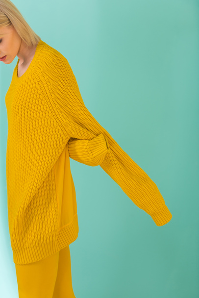 przycięte zdjęcie kobiety w żółty sweterek pozowanie na niebieskim tle - Zdjęcie, obraz