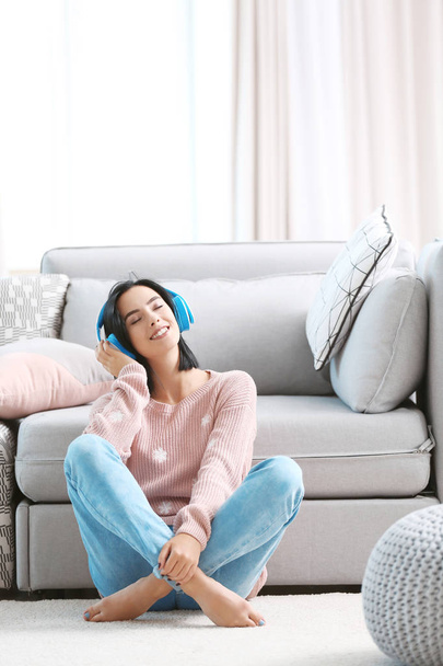 Jeune femme écoutant de la musique dans les écouteurs à la maison
 - Photo, image