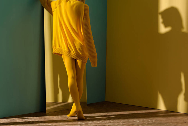 cropped shot of woman in yellow sweater and tights standing at mirror - Fotó, kép