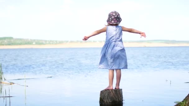 Jong meisje met jurk tegoed met open armen op lakeside - Video