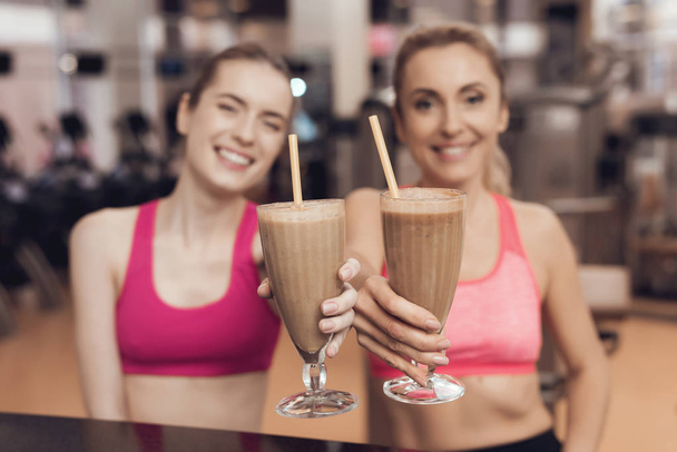 Mother and daughter in sportswear drinking protein shakes at gym - Foto, Imagen