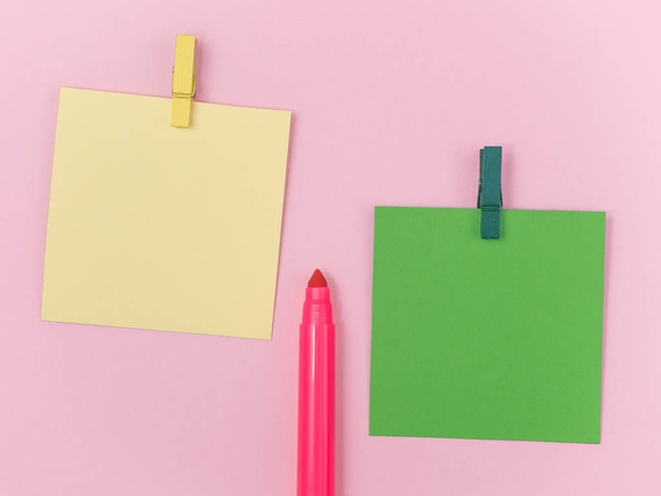ροζ μαγικό στυλό με πράσινο και κίτρινο χαρτί σημείωμα και με κλιπ χαρτιού σε ροζ φόντο, ελάχιστη έννοια και ομοιότητες διαφορές - Φωτογραφία, εικόνα