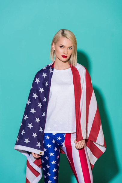 portrait of young woman in white shirt with american flag on blue backdrop, celebrating 4th july concept - Foto, afbeelding