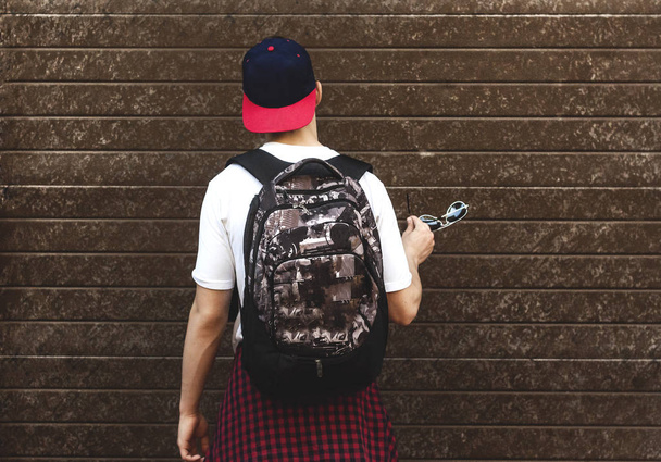  genç bir duvarının yakınında bekleyen bir sırt çantası ile - Fotoğraf, Görsel