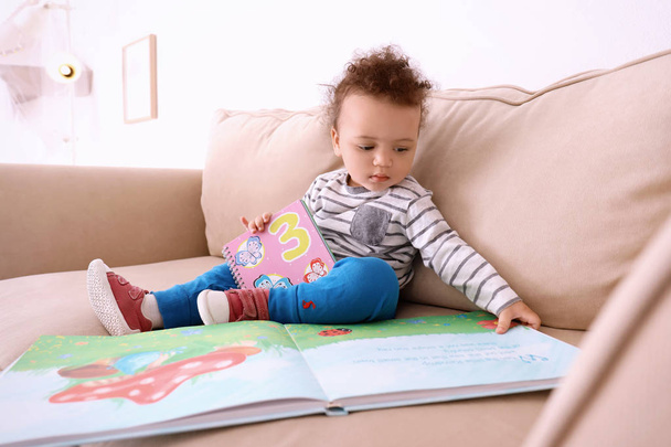 little child with colorful book at sofa - Fotó, kép