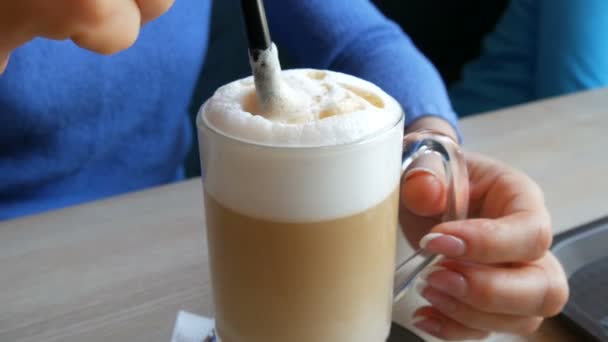 Female hands are stirring the air froth from the latte with straw - Footage, Video