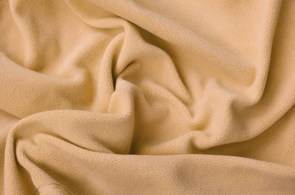 Η κουβέρτα γούνινο πορτοκαλί φλις ύφασμα. Ένα φόντο του υλικού φωτός πορτοκαλί μαλακό φλις φούτερ με πολλή ανακούφιση πτυχώσεις - Φωτογραφία, εικόνα