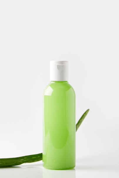 Nahaufnahme von Bio-Duschgel in Flasche und Aloe-Vera-Blatt auf weißer Oberfläche - Foto, Bild