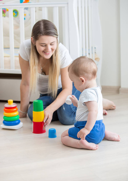 Beautiful young woman sitting with her 10 months old son and playing with toys - Photo, Image