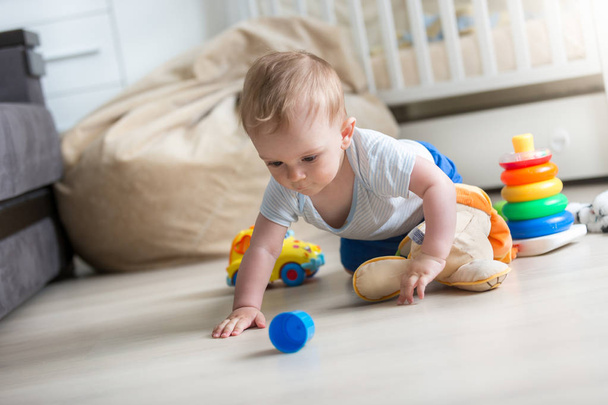 Αξιολάτρευτο μικρό παιδί αγόρι σέρνεται στο πάτωμα και να παίζει με τα παιχνίδια - Φωτογραφία, εικόνα