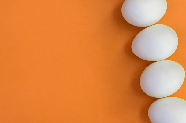 Quelques œufs de Pâques blancs sur un fond orange vif
 - Photo, image