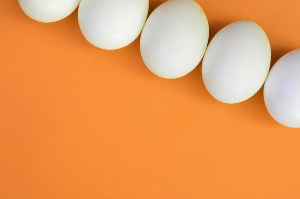 A few white easter eggs on a bright orange background - Foto, Imagen