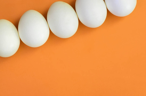 Alguns ovos de páscoa branca em um fundo laranja brilhante
 - Foto, Imagem