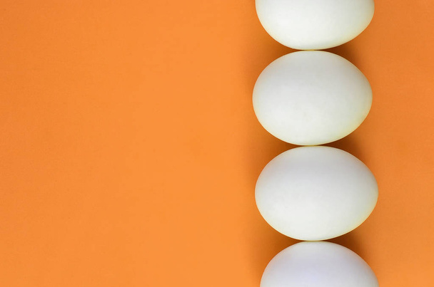A few white easter eggs on a bright orange background - Foto, afbeelding