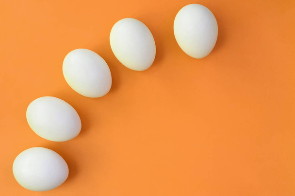 Quelques œufs de Pâques blancs sur un fond orange vif
 - Photo, image