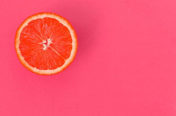 Bovenaanzicht van een segment van een grapefruit op lichte achtergrond in licht roze kleur. Een verzadigde citrus textuur afbeelding - Foto, afbeelding