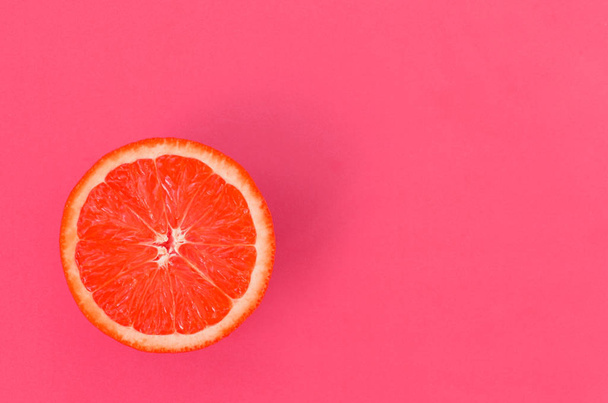 Bovenaanzicht van een segment van een grapefruit op lichte achtergrond in licht roze kleur. Een verzadigde citrus textuur afbeelding - Foto, afbeelding